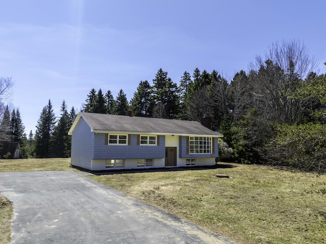 raised ranch with a chimney, a front lawn, and driveway