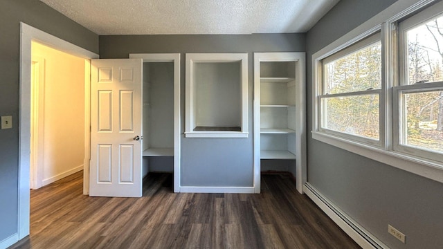 unfurnished bedroom with a baseboard radiator, baseboards, a textured ceiling, and dark wood-style floors