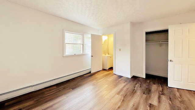 unfurnished bedroom with wood finished floors, a closet, baseboards, a textured ceiling, and baseboard heating