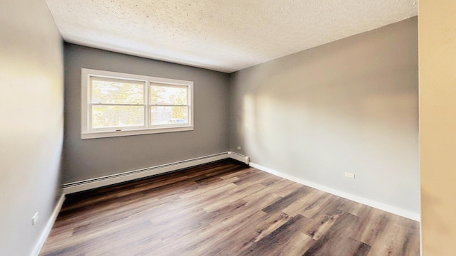 empty room with baseboards, wood finished floors, a textured ceiling, and baseboard heating