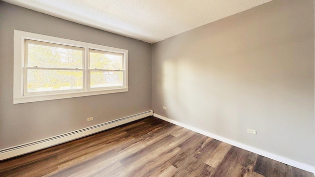 unfurnished room featuring a baseboard heating unit, dark wood finished floors, and baseboards
