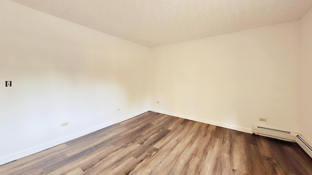 unfurnished room with a baseboard radiator, baseboards, and wood finished floors