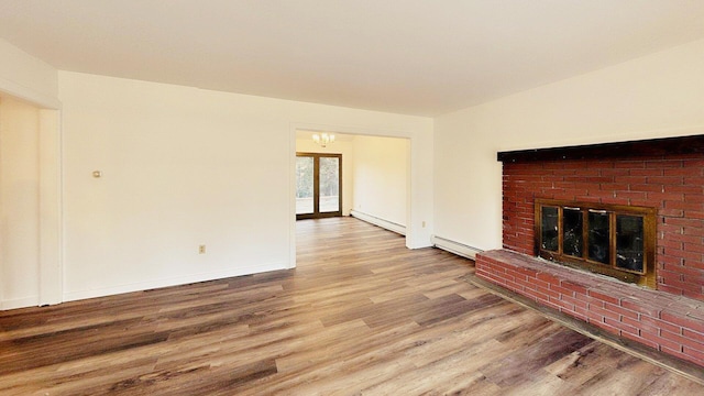 unfurnished living room with baseboard heating, a baseboard heating unit, wood finished floors, and a fireplace