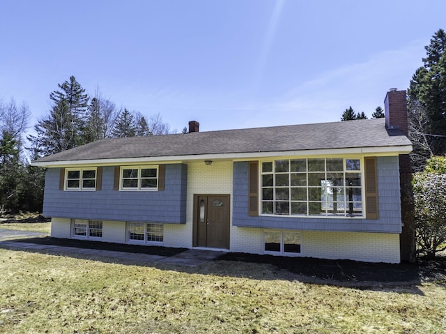 bi-level home with a chimney and a front yard