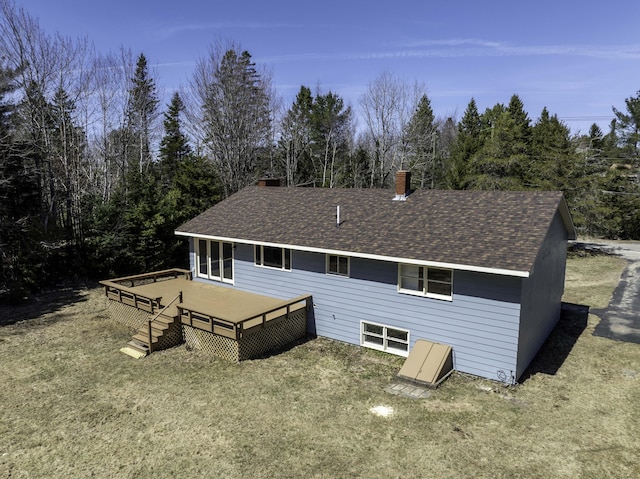 back of property with a wooden deck, a shingled roof, and a chimney