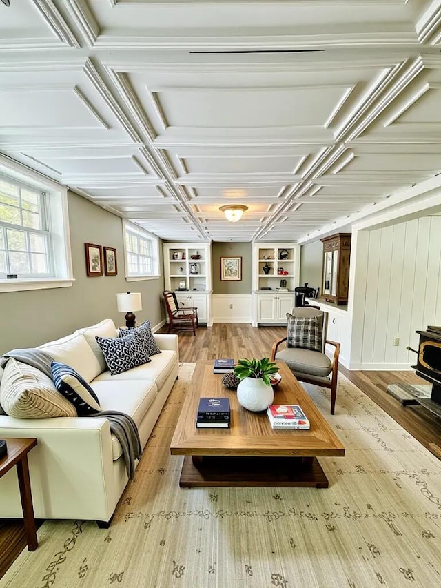 living room with light wood-style floors, a wood stove, and built in shelves