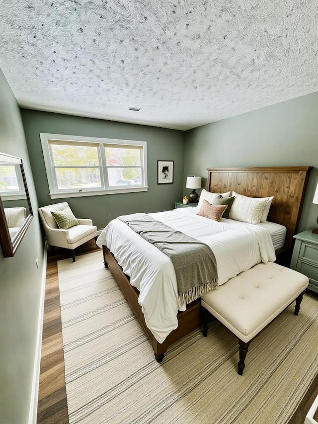 bedroom with light wood-style flooring, visible vents, and a textured ceiling