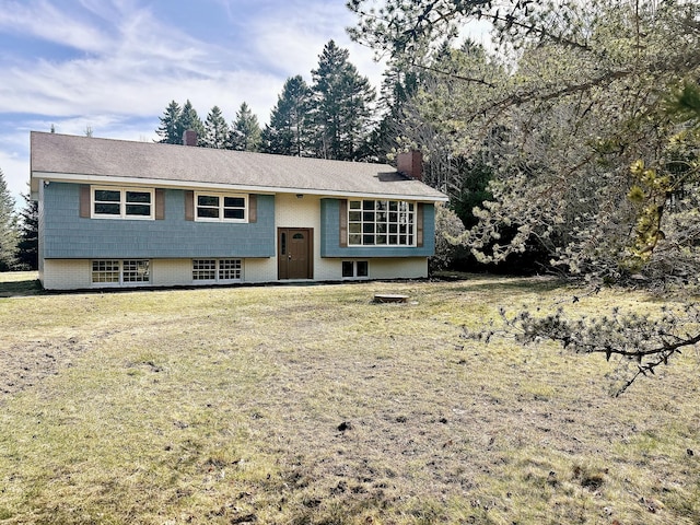 raised ranch with a chimney, a front lawn, and brick siding