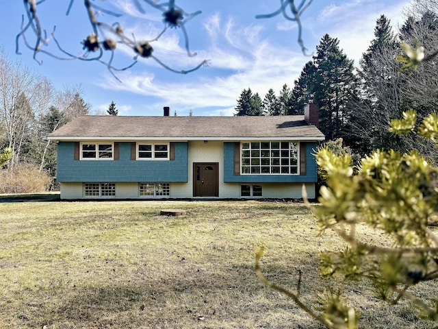 split foyer home with a front lawn, brick siding, and a chimney