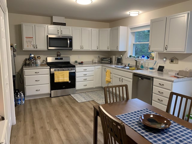26 Townsend Ln, Boothbay, ME 04537 - kitchen with white cabinetry, a sink, light countertops, stainless steel appliances, and light wood-style flooring
