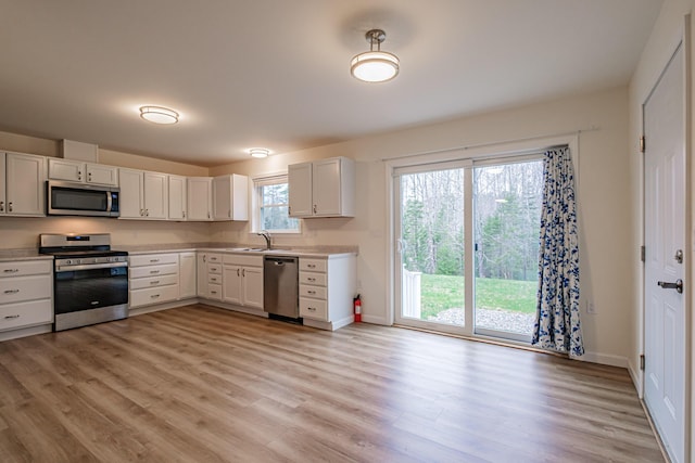 26 Townsend Ln, Boothbay, ME 04537 - kitchen with light wood-type flooring, light countertops, white cabinetry, a sink, and stainless steel appliances