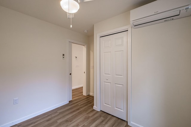 26 Townsend Ln, Boothbay, ME 04537 - unfurnished bedroom with a closet, baseboards, an AC wall unit, and light wood finished floors