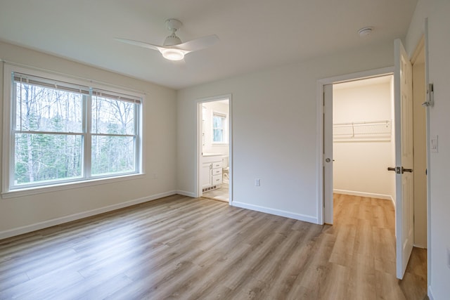 26 Townsend Ln, Boothbay, ME 04537 - unfurnished bedroom with a closet, baseboards, a walk in closet, ceiling fan, and light wood-style flooring