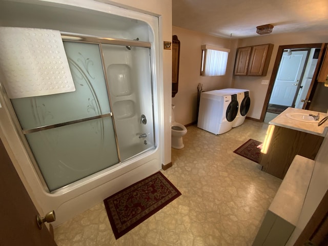 full bathroom featuring washing machine and dryer, vanity, enclosed tub / shower combo, and toilet