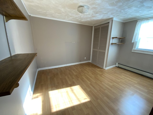 unfurnished bedroom featuring crown molding, light hardwood / wood-style floors, a textured ceiling, a baseboard radiator, and a closet