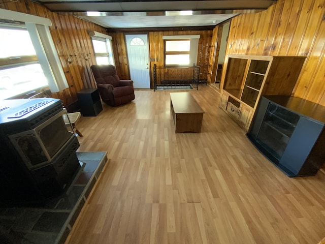 living room featuring plenty of natural light, wooden walls, a wood stove, and light wood-type flooring