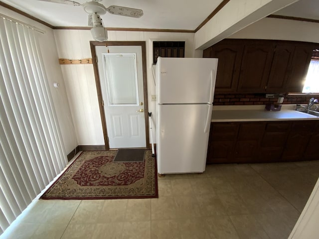 kitchen featuring sink, white fridge, ceiling fan, dark brown cabinetry, and crown molding