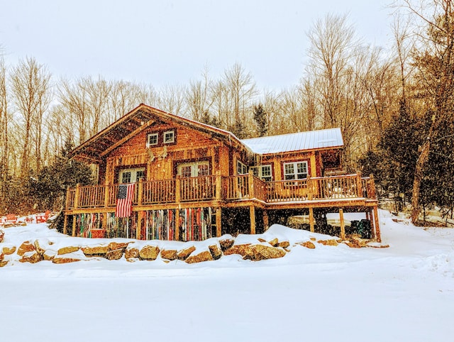 snow covered property featuring metal roof and a wooden deck