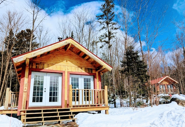 snow covered structure with french doors and an outdoor structure