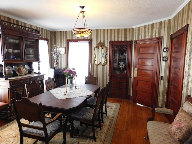 dining room with ornamental molding, hardwood / wood-style floors, and a textured ceiling