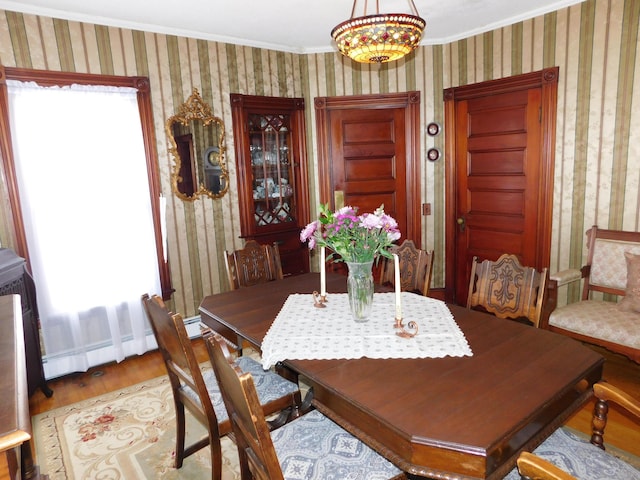 dining area featuring a baseboard heating unit, hardwood / wood-style flooring, and ornamental molding