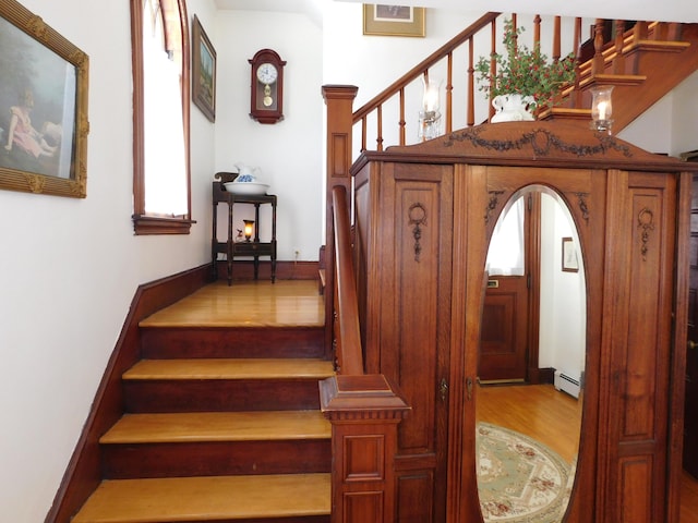 stairs featuring a healthy amount of sunlight, hardwood / wood-style floors, and baseboard heating