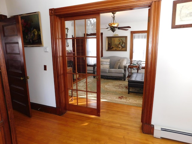 entryway with baseboard heating, ceiling fan, and light hardwood / wood-style flooring