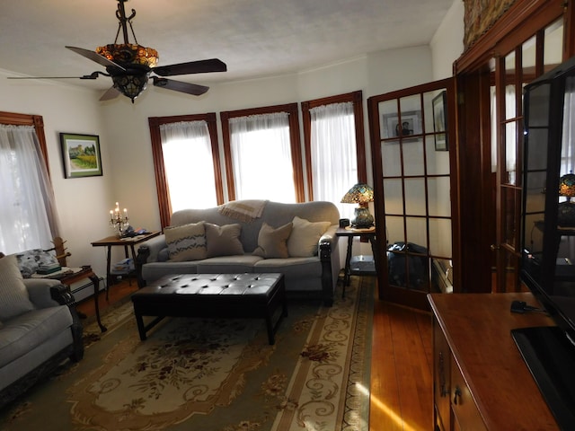 living room featuring dark wood-type flooring, ceiling fan, and a baseboard heating unit