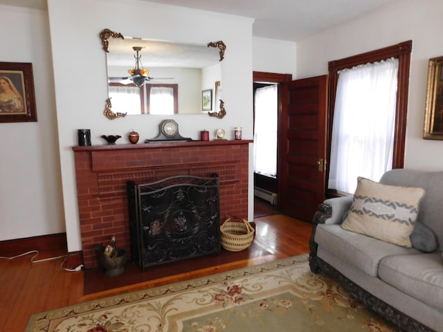 living room with hardwood / wood-style flooring, a fireplace, and a baseboard heating unit