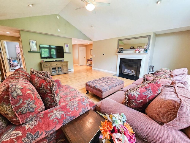 living room featuring a fireplace with flush hearth, a ceiling fan, high vaulted ceiling, light wood-type flooring, and baseboards