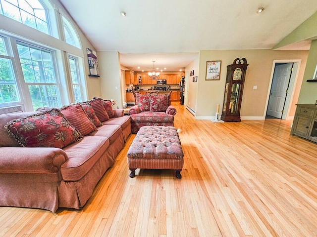 living area featuring baseboards, high vaulted ceiling, light wood finished floors, and an inviting chandelier