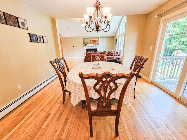 dining room featuring baseboards, a fireplace, a baseboard radiator, and light wood-style floors