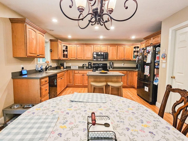 kitchen with a center island, dark countertops, glass insert cabinets, a sink, and black appliances