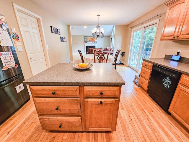 kitchen with dark countertops, black appliances, light wood-style floors, and a center island