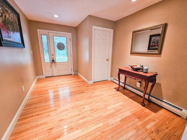 foyer with baseboard heating, light wood-style flooring, and baseboards