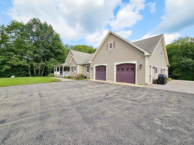 view of front of property with a garage, driveway, a front lawn, and a porch