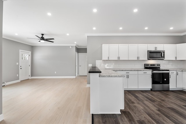 kitchen featuring hardwood / wood-style flooring, white cabinetry, appliances with stainless steel finishes, and decorative backsplash