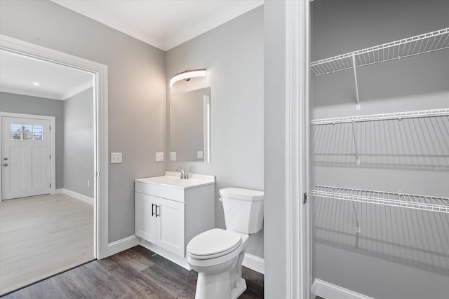 bathroom featuring vanity, wood-type flooring, ornamental molding, and toilet