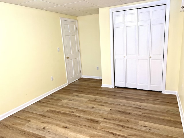 unfurnished bedroom with hardwood / wood-style flooring, a closet, and a drop ceiling