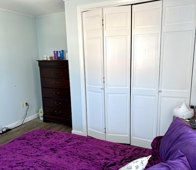 bedroom featuring dark wood-type flooring, ornamental molding, and a closet