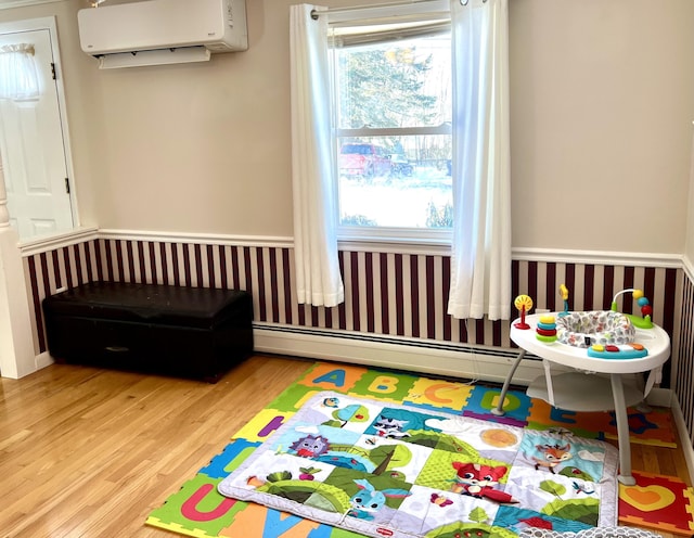 game room featuring a baseboard radiator, light hardwood / wood-style floors, and a wall mounted AC