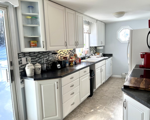 kitchen with sink, baseboard heating, white cabinetry, white refrigerator, and decorative backsplash