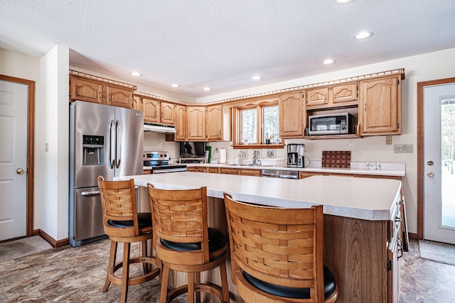 kitchen featuring light countertops, appliances with stainless steel finishes, a wealth of natural light, and under cabinet range hood