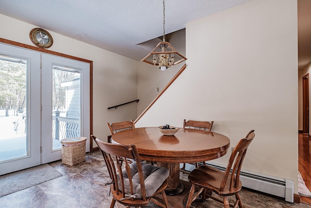 dining area featuring stone finish floor, an inviting chandelier, a baseboard heating unit, and a textured ceiling