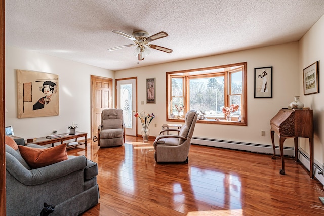 sitting room featuring a textured ceiling, ceiling fan, wood finished floors, and baseboards