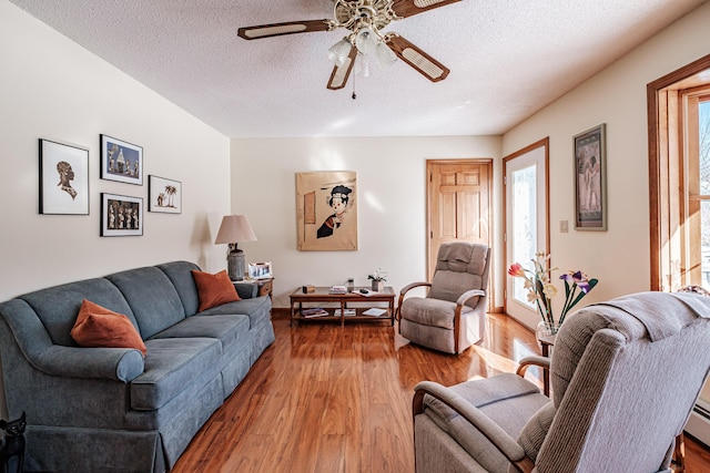 living area with a ceiling fan, a textured ceiling, and wood finished floors