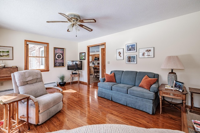 living room with a textured ceiling, a baseboard radiator, wood finished floors, and a ceiling fan