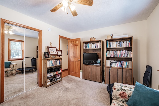 sitting room with a ceiling fan, carpet flooring, and a textured ceiling