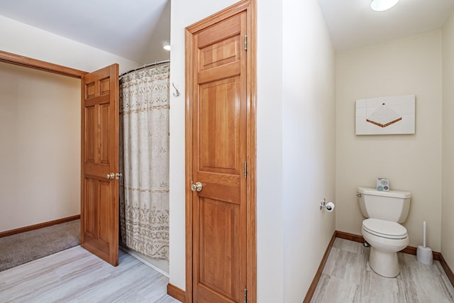 full bathroom featuring a shower with curtain, wood finished floors, toilet, and baseboards