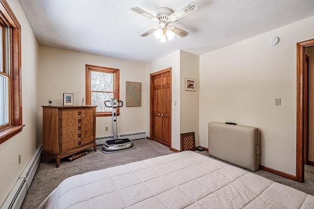 carpeted bedroom with a baseboard heating unit, a textured ceiling, and baseboards